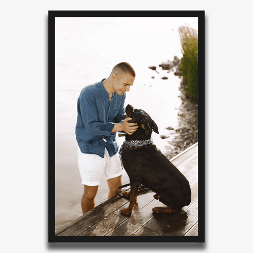 Foto Poster: Mann mit großem schwarzem Hund am Steg, im schwarzen Rahmen